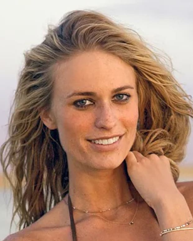 Julie Henderson poses in front of the Chilean desert and smiles at the camera in a brown string bikini.